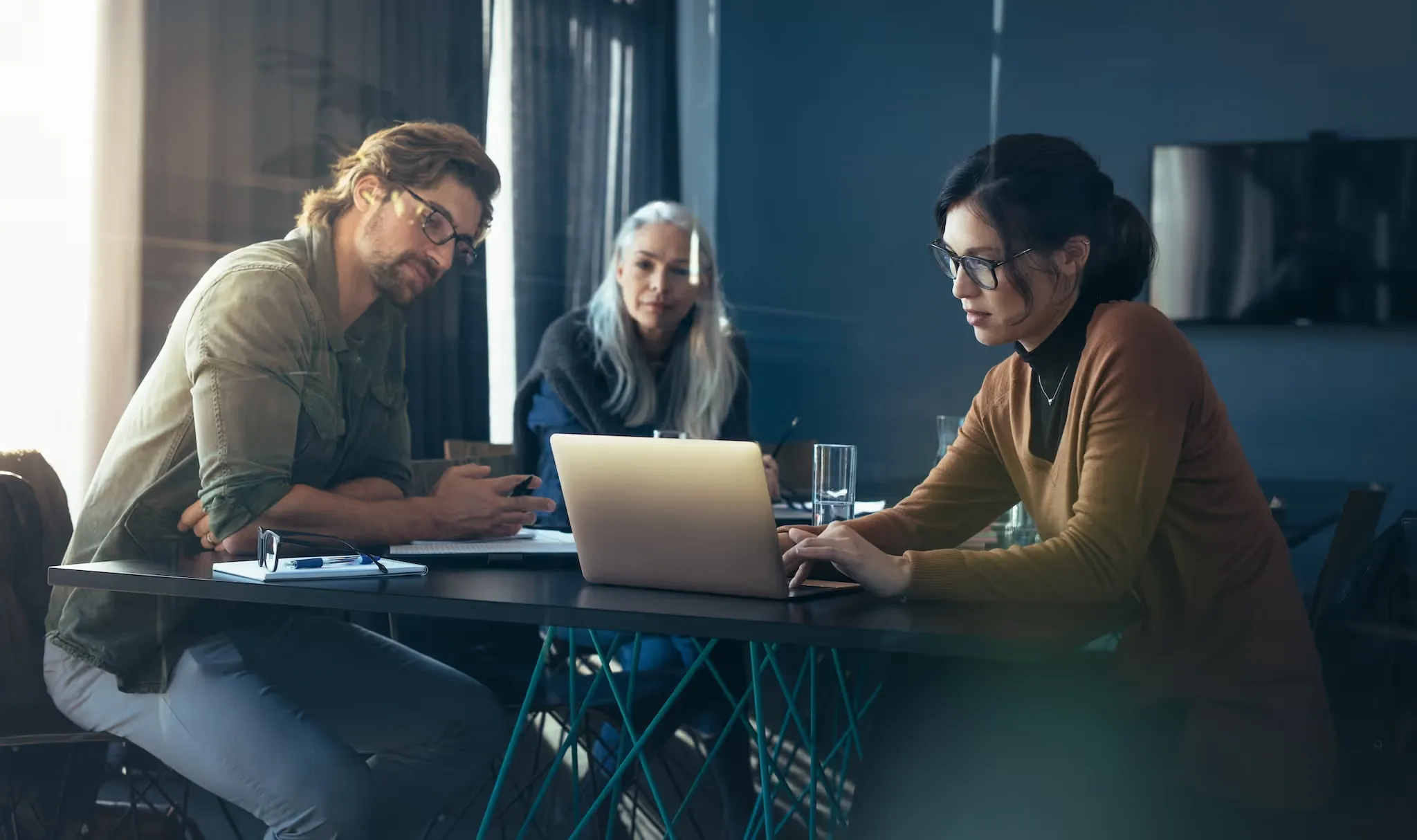 Ein Team arbeitet konzentriert gemeinsam an einem Tisch mit Laptop